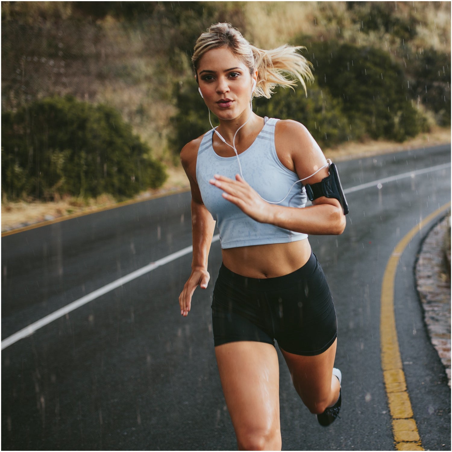 Läuferin läuft im Regen mit Musik sportlich