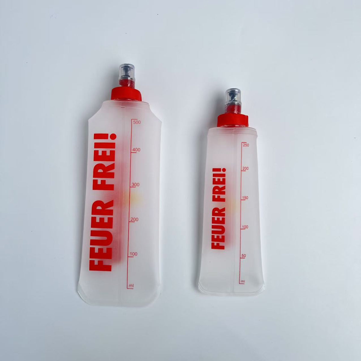 SportBrennstoff BEGLEITER - Trinkflasche in zwei Größen mit rotem Aufdruck 'FEUER FREI!', flexibel, tropfsicher und ideal für Outdoor-Aktivitäten.