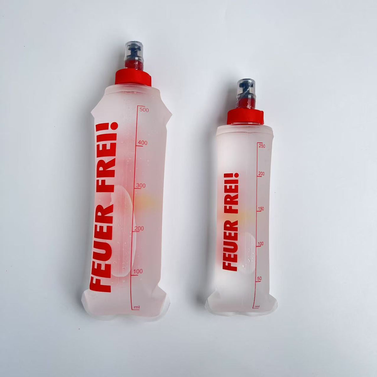 SportBrennstoff BEGLEITER - Trinkflasche in zwei Größen mit rotem Deckel und Skala, flexibel und tropfsicher für Outdoor-Aktivitäten.