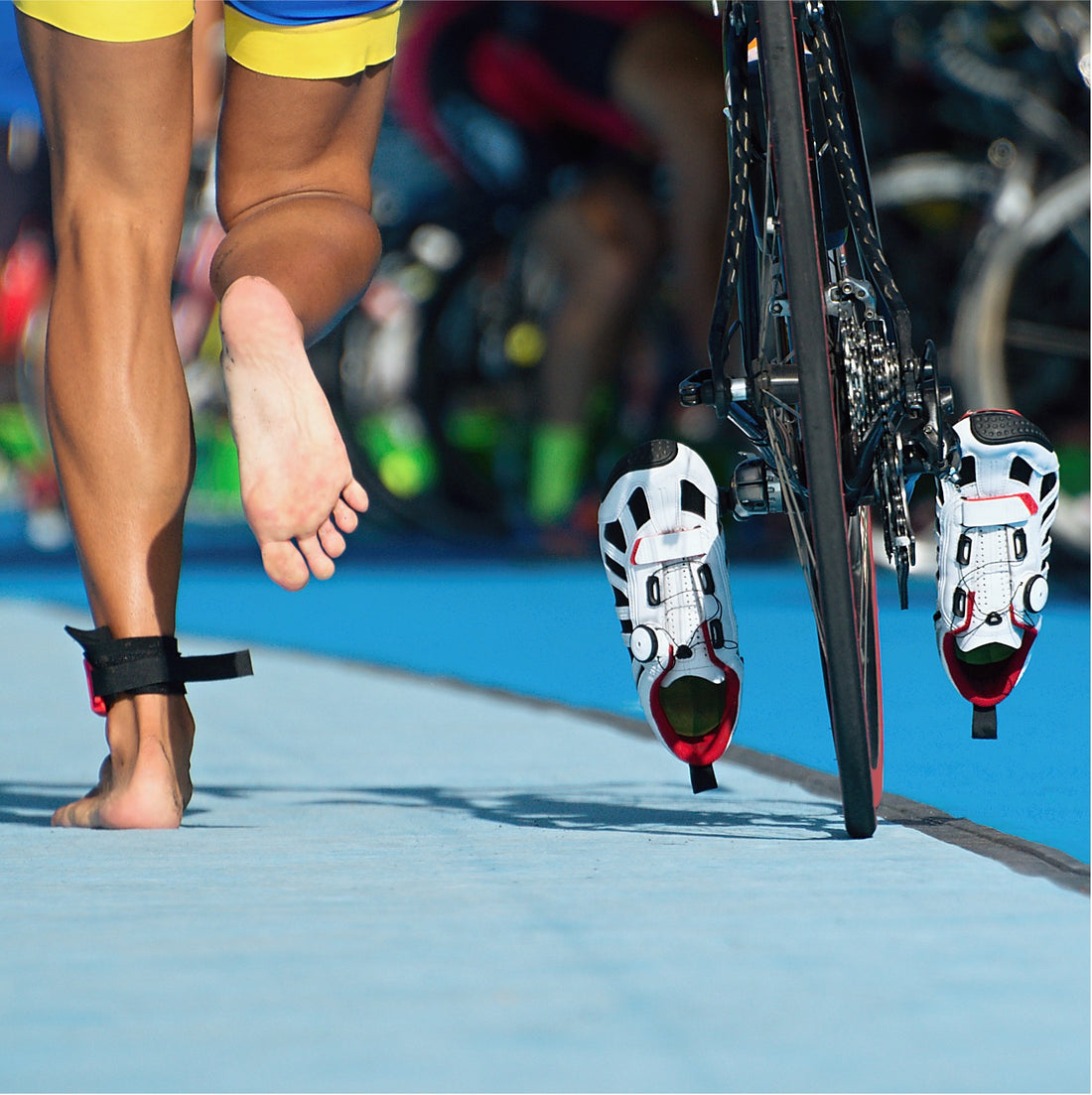 Triathlet läuft in der Wechselzone mit Fahrrad