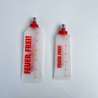 SportBrennstoff BEGLEITER - Trinkflasche in zwei Größen mit rotem Aufdruck 'FEUER FREI!', flexibel, tropfsicher und ideal für Outdoor-Aktivitäten.
